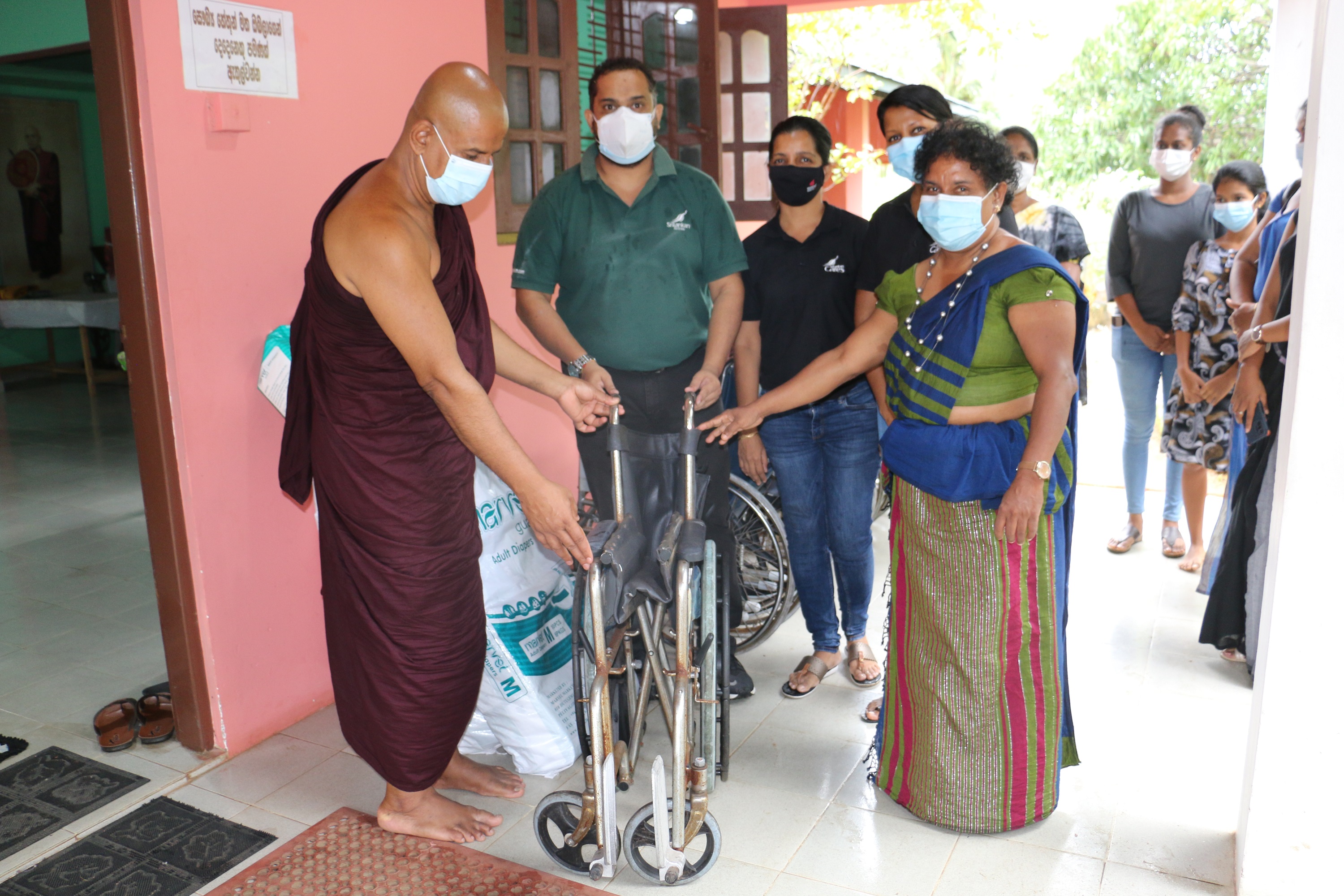 Handing the repurposed wheelchairs and daily essentials to Sarana Buddhist Foundation
